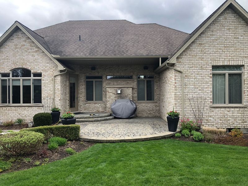 Stone patio and lawn beside a brick home